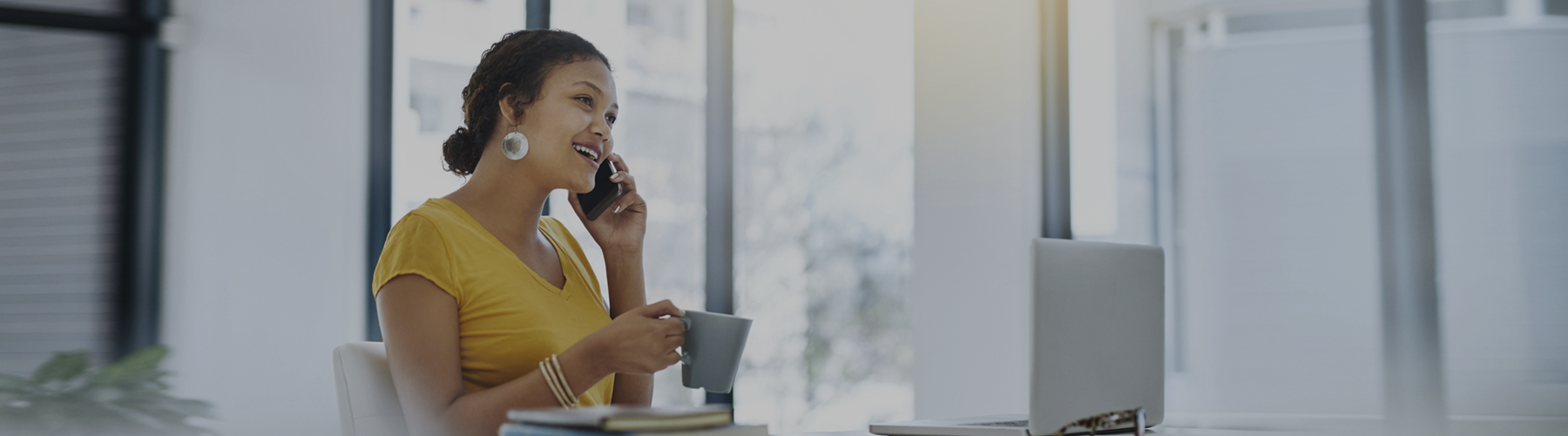Woman talks on a phone while sitting at a desk